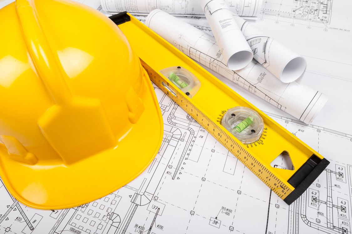 Hard hat and spirit level on rolled blueprints