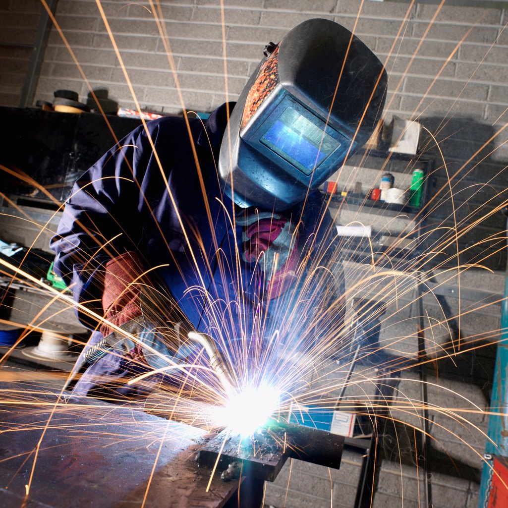 Welder in protective gear working with sparks flying