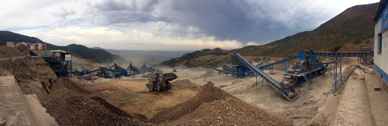 Panoramic view of an open-pit mining site with conveyor belts and machinery