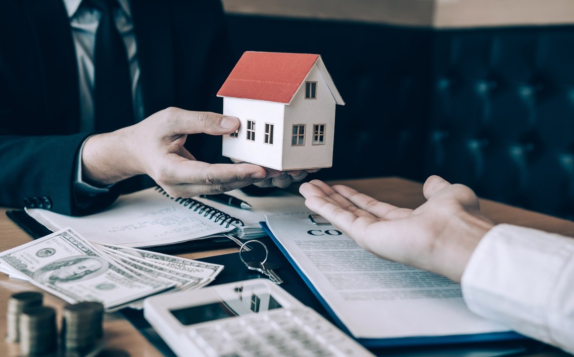 Hands exchanging a model house — property services